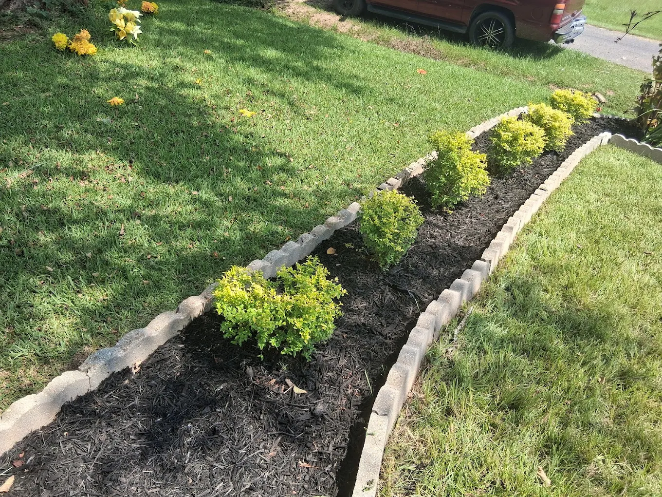 Side-by-side comparison of a backyard showing before and after stone patio installation behind a two-story house with wooden steps and a screened porch.